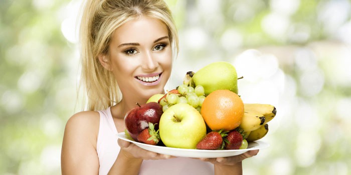 Девушка держит блюдо с фруктами и ягодами