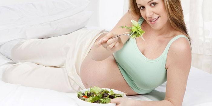 Беременная девушка ест салат