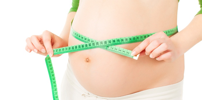 Девушка измеряет объем талии после родов