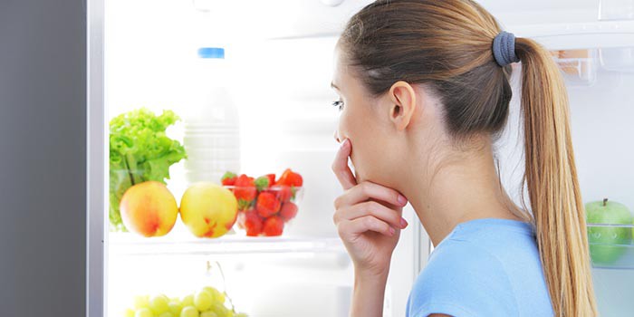 Девушка выбирает продукты в холодильнике