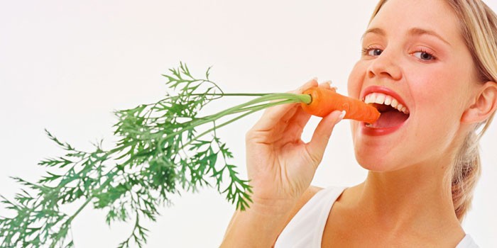 Девушка кушает морковь