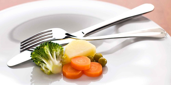 Маленькая порция овощей на тарелке и вилка
