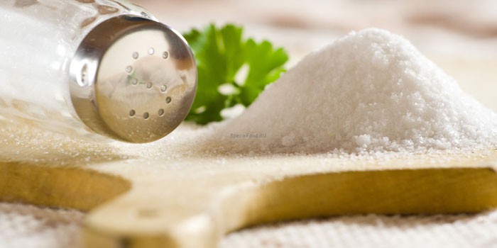 Кухонная соль на разделочной доске и солонка 