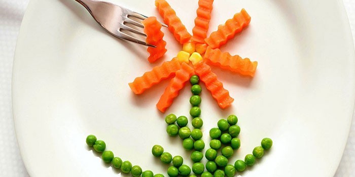 Цветок из моркови и зеленого горошка на тарелке