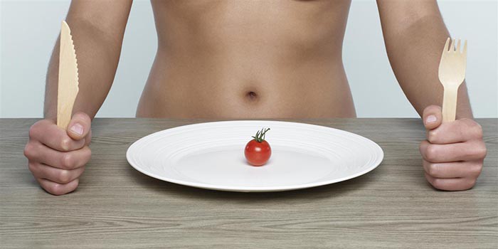 Девушка за столом и маленький помидор на тарелке